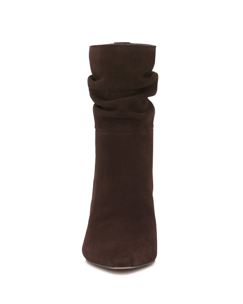 The Vince Camuto Grenna Slouchy Bootie is shown from the front in dark brown suede, featuring a slightly slouched upper and a rounded toe, set against a white background.