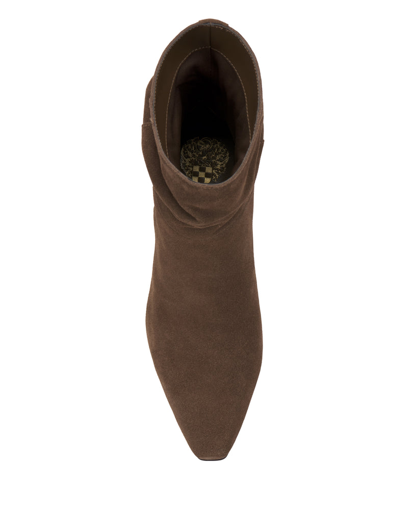 Top view of the Vince Camuto Grenna Slouchy Bootie, a single brown suede ankle boot featuring a pointed toe and a patterned insole, displayed on a white background.