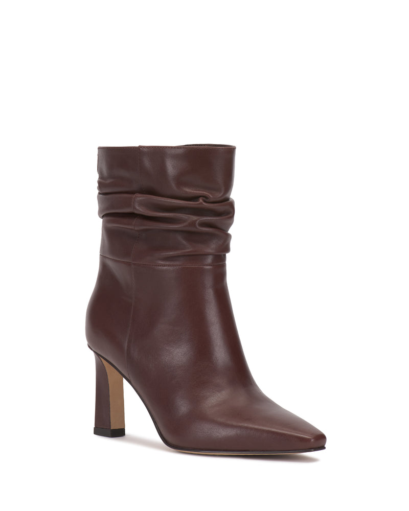 The Vince Camuto Grenna Slouchy Bootie is a brown leather ankle boot featuring a mid-height block heel, pointed toe, and a slightly slouched shaft, displayed on a white background.
