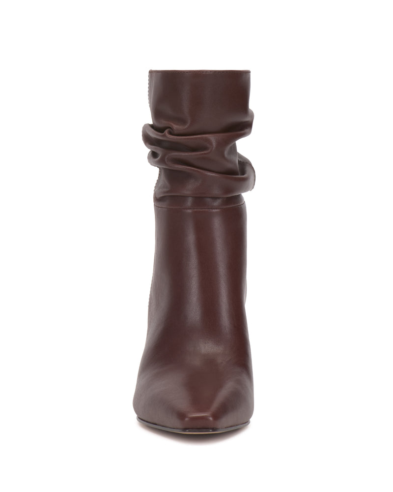 A front-facing view of the Vince Camuto Grenna Slouchy Bootie in brown leather, featuring a pointed toe and a slightly scrunched shaft, displayed on a white background.