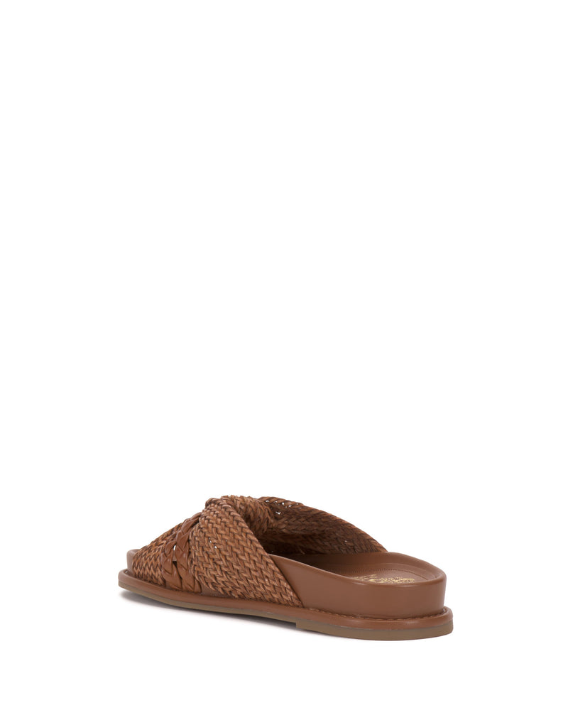 The Vince Camuto Gryfynn Slide, featuring a brown woven upper and cushioned sole in a flat slip-on design, is shown from a rear side angle on a white background.
