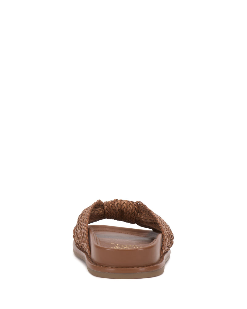 The Vince Camuto Gryfynn Slide, a brown woven sandal with a braided strap and flat sole, is shown from the back against a white background.