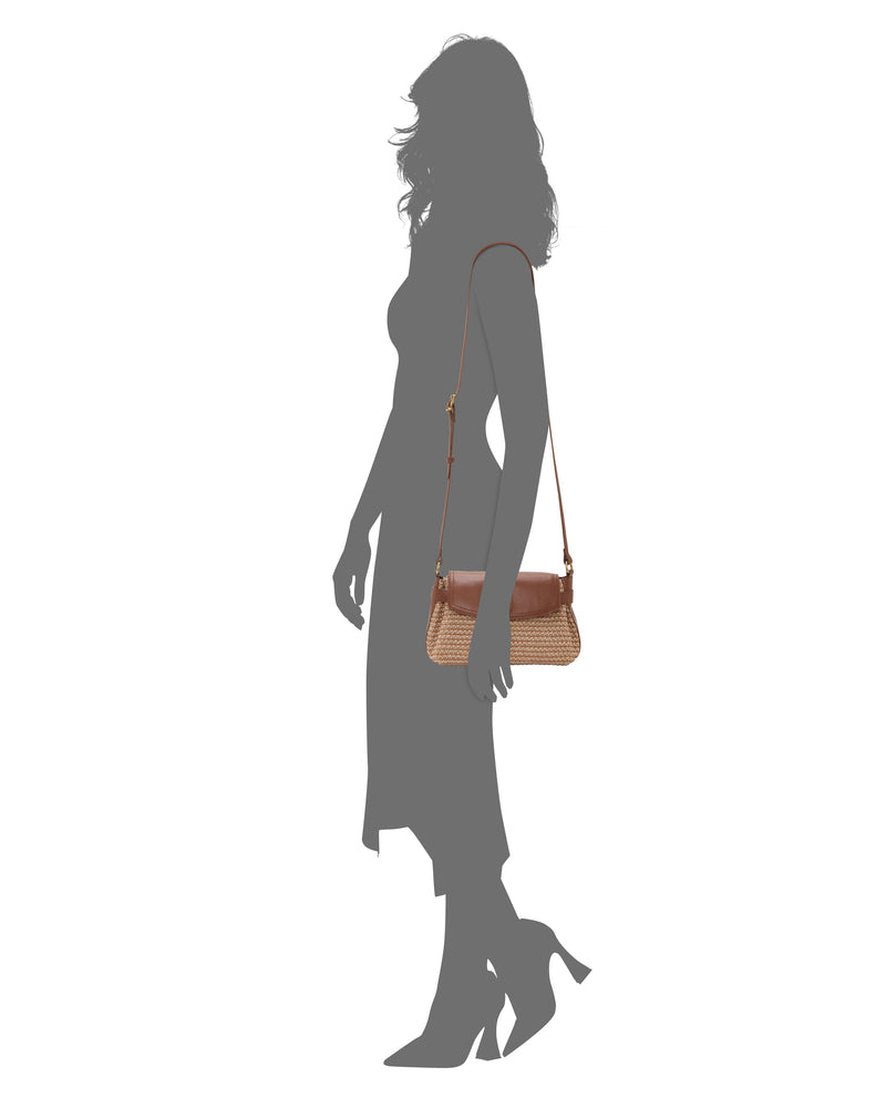 A woman in a dress and heels holds the Vince Camuto Hadley Crossbody Bag, a stylish brown woven handbag with a shoulder strap, ideal for effortless everyday style, set against a plain white background.