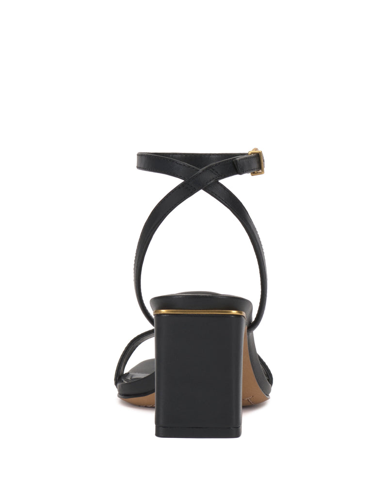 The Hamda Sandal by Vince Camuto is a black block-heel sandal with a square gold-accented heel and minimalist design. Thin adjustable ankle straps cross elegantly and buckle at the side, ensuring a secure, stylish fit.