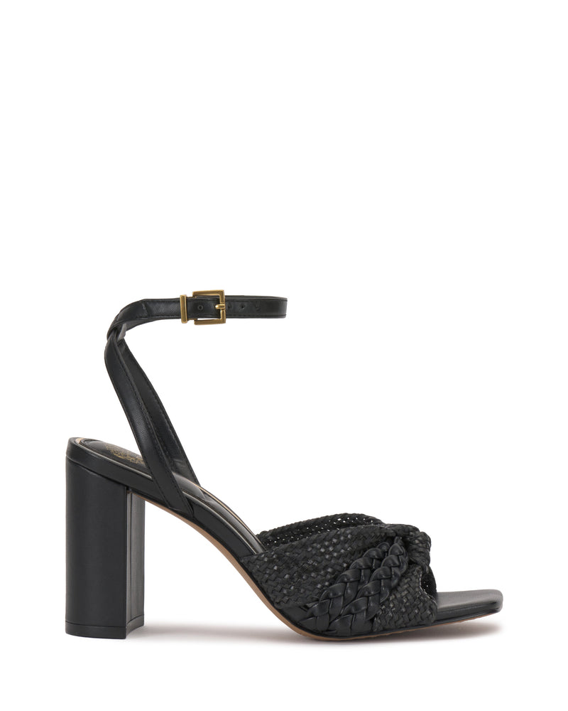The Vince Camuto Hanlea Sandal showcases a black braided leather front strap, closed back, ankle strap with gold buckle, and a thick block heel for stylish support.