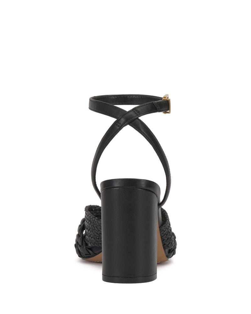 The Vince Camuto Hanlea Sandal in black is shown from the back, featuring a block heel, braided side detailing for texture, and thin ankle straps that cross and buckle at the side.