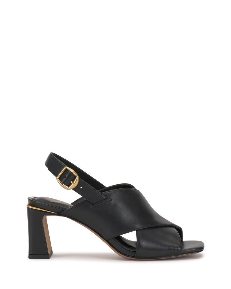 Introducing the Harlynn Sandal by Vince Camuto—crafted in black leather and featuring open toes, crisscross front straps, and a slingback strap with a gold buckle. This stylish sandal is set on a block heel and finished with a neutral tan-outlined sole. Shown against a white background.