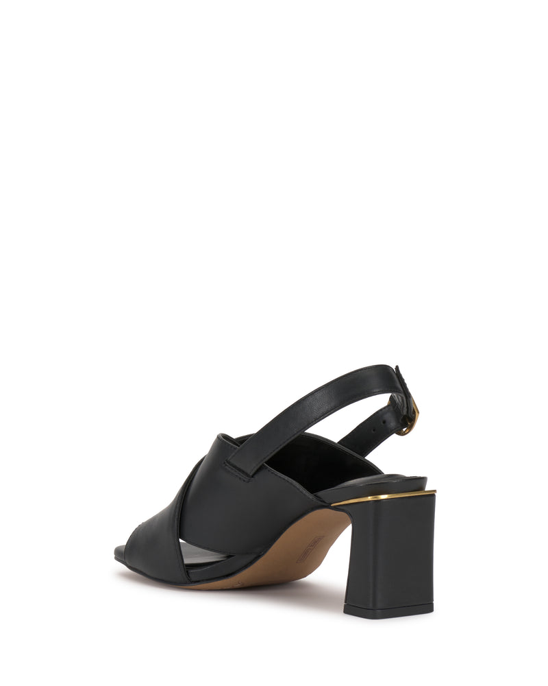 The Harlynn Sandal by Vince Camuto is a black open-toe slingback featuring thick, crisscross straps and a square block heel accented with gold trim on the sole, shown from the back against a white background.