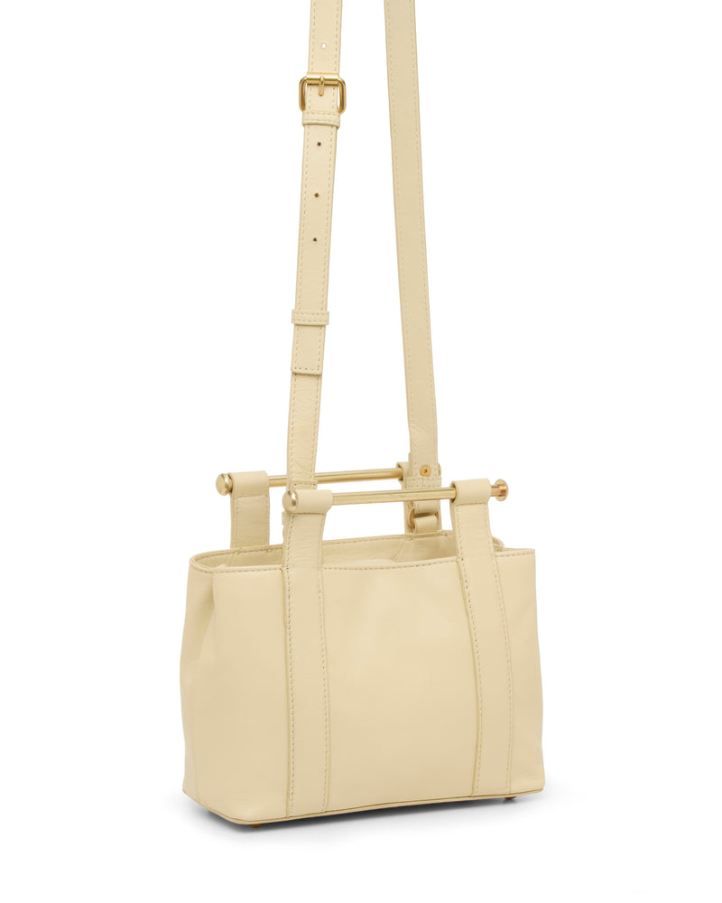 The Jayda Satchel Bag by Vince Camuto is a small, rectangular cream leather bag with two top handles, gold-tone bar accents, and an adjustable shoulder strap. This structured bag offers a smooth finish and elegant style.
