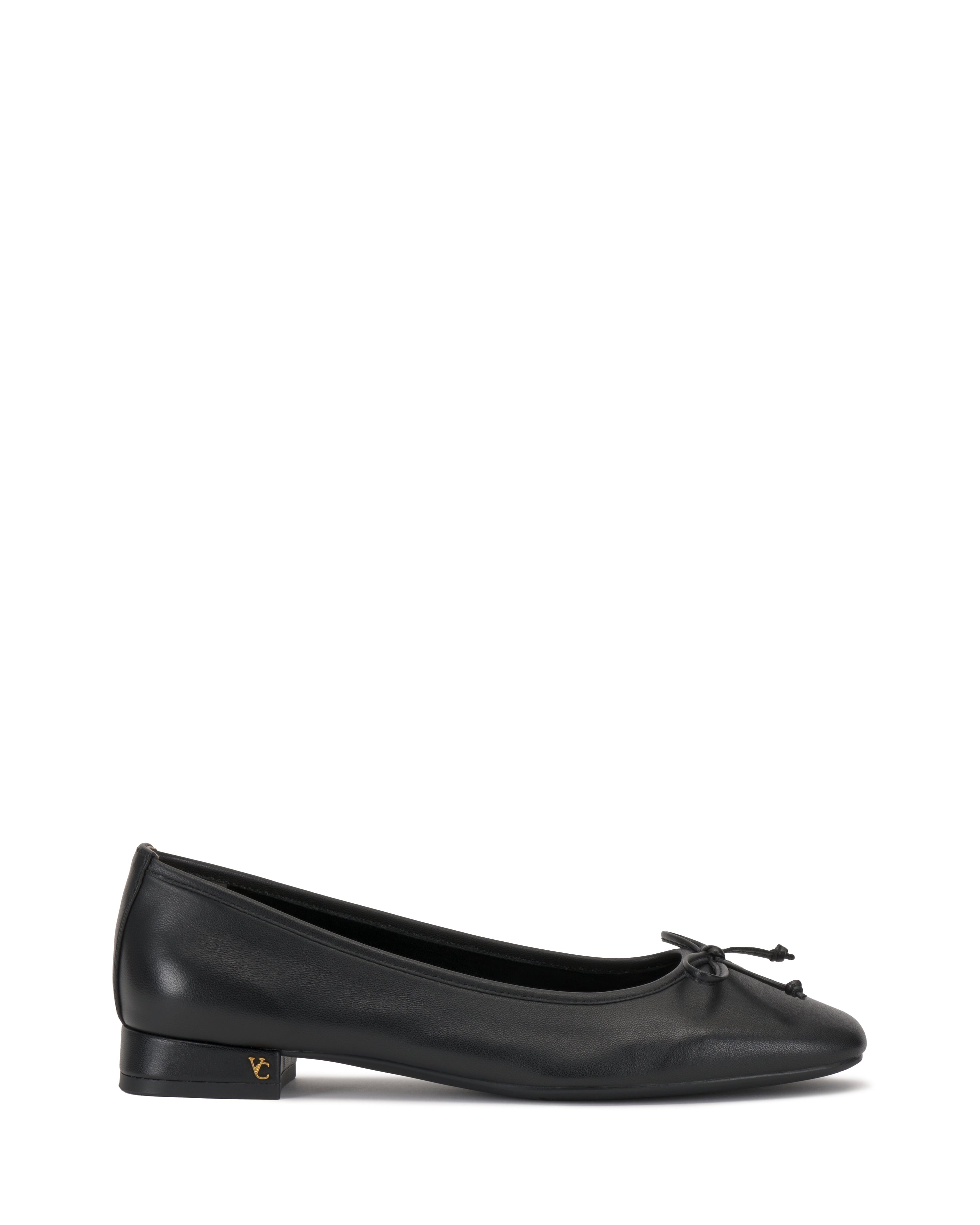 The Vince Camuto Jenlea Ballet Flat features black leather, a low heel, rounded toe, front bow, and subtle gold logo on the outer heel. Displayed against a white background.