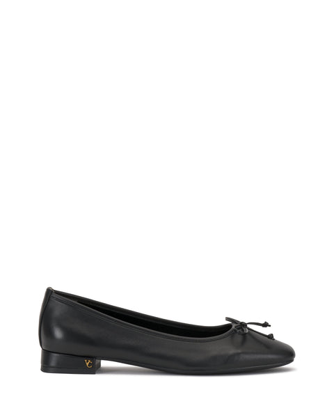 The Vince Camuto Jenlea Ballet Flat is a black leather shoe with a low block heel, bow accent on the rounded toe, and a subtle gold logo near the heel, shown against a white background.