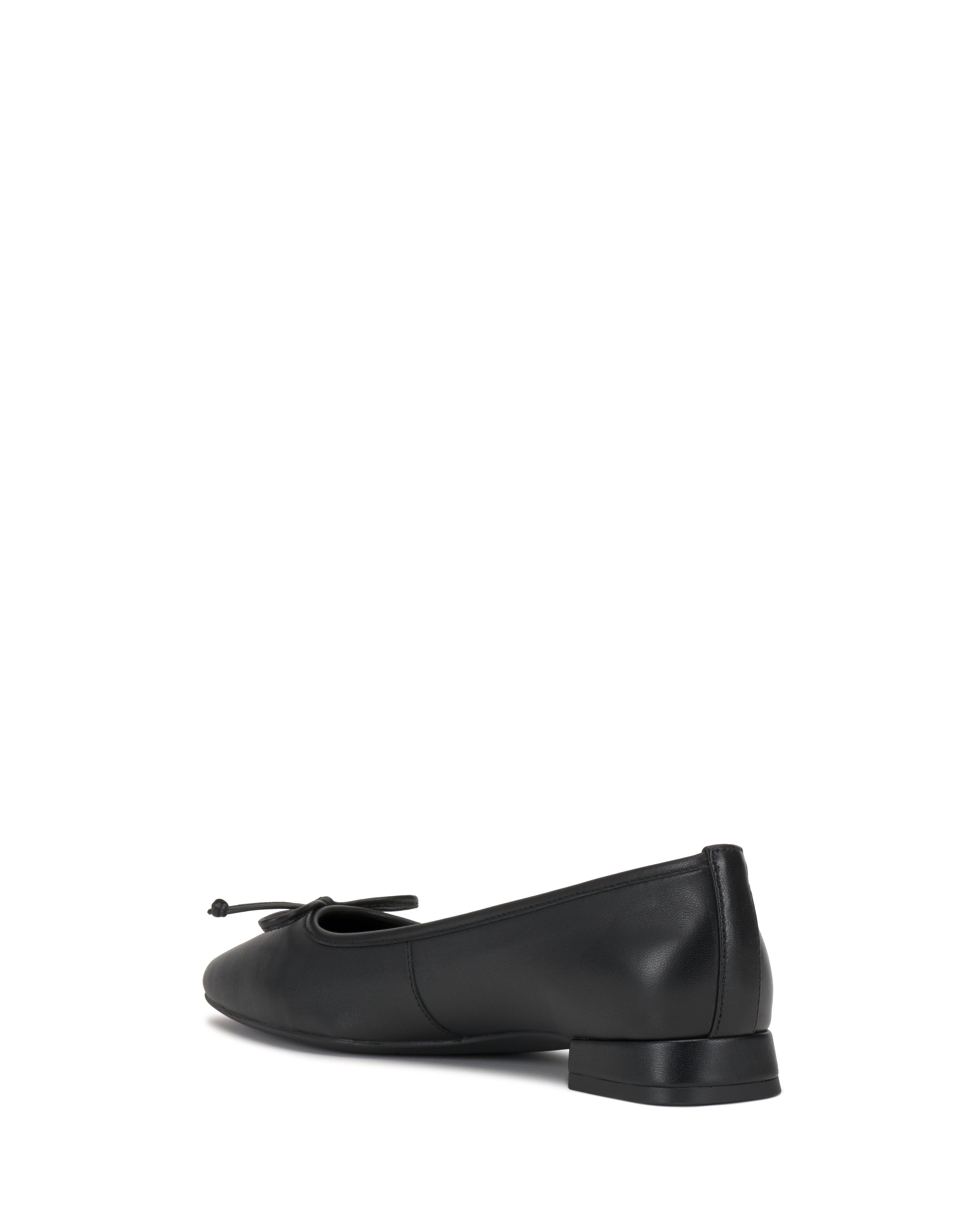 The Vince Camuto Jenlea Ballet Flat is a black leather shoe with a small heel and a bow on the toe, displayed from a rear side angle on a white background.