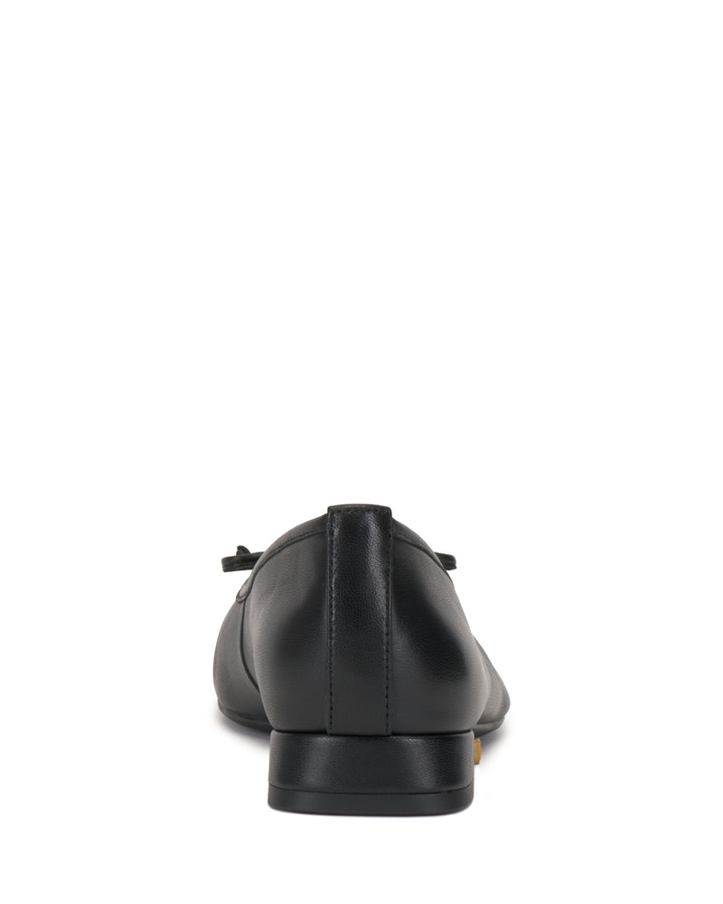 The Vince Camuto Jenlea Ballet Flat is a black leather flat shoe with a low heel, shown from the back on a white background. A small decorative bow accents the upper.