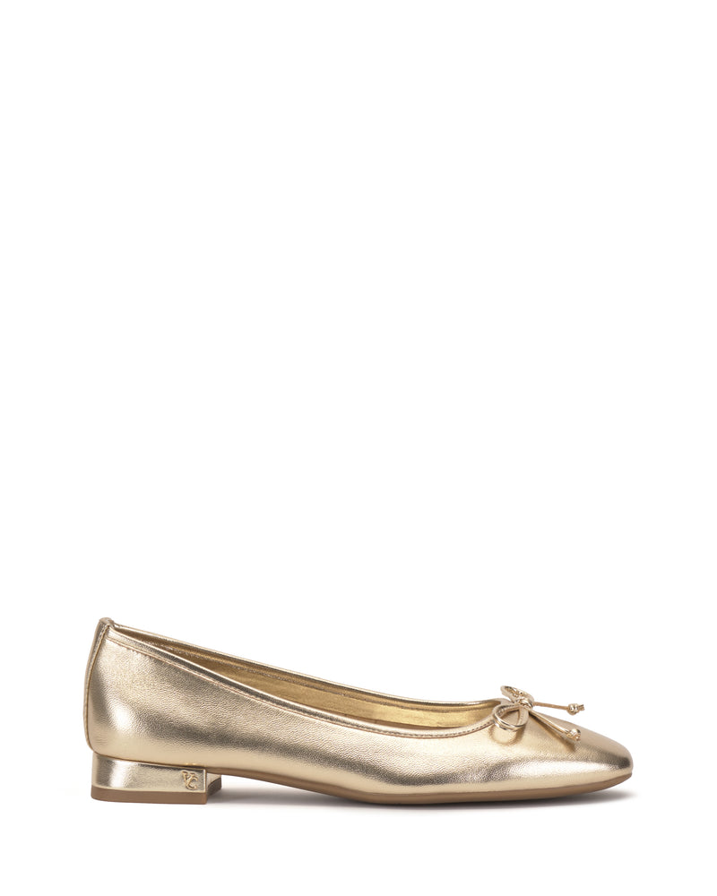The Vince Camuto Jenlea Ballet Flat, in gold with a small toe bow and low block heel, is shown in side profile on a white background.
