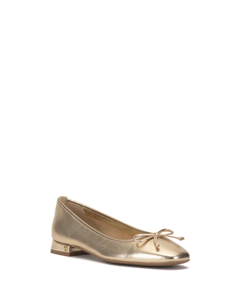 The Jenlea Ballet Flat by Vince Camuto features a gold metallic finish, small heel, rounded toe, and front bow for a subtle shine and minimalist look.