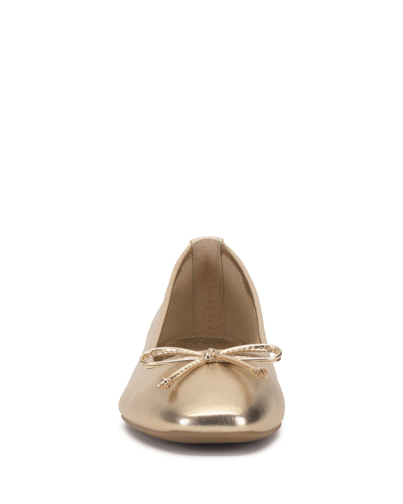 The Jenlea Ballet Flat by Vince Camuto is a gold shoe with a small matching bow on the toe, pictured from the front on a white background.
