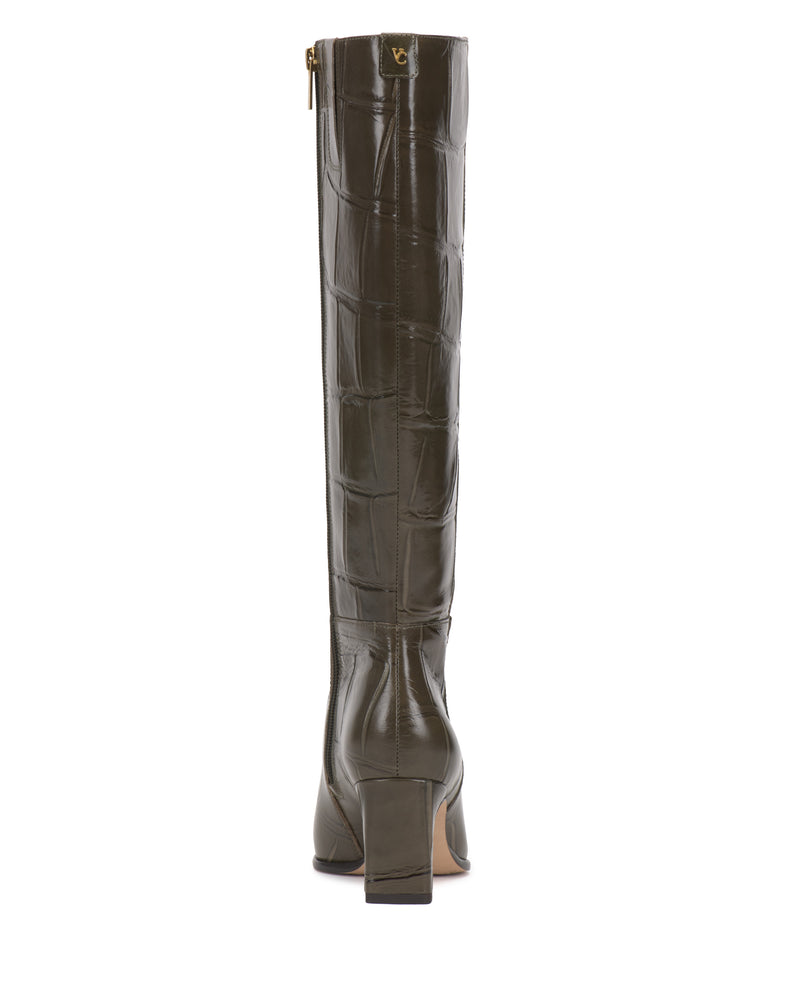 The Jorela Narrow Calf Knee High Boot by Vince Camuto is displayed from the back, showcasing its tall, dark green faux-crocodile leather design with a block heel and a gold zipper pull near the top.