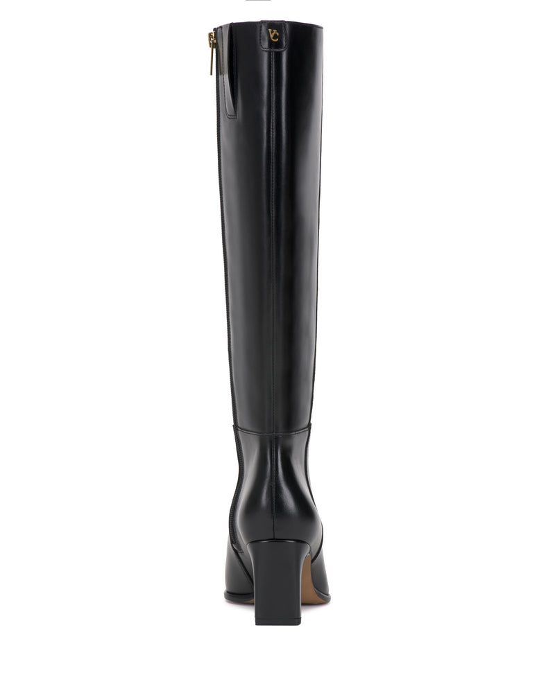 The Vince Camuto Jorela Knee High Boot is a tall black leather boot with a block heel, shown from the back. A gold zipper and a small logo detail near the top are visible.