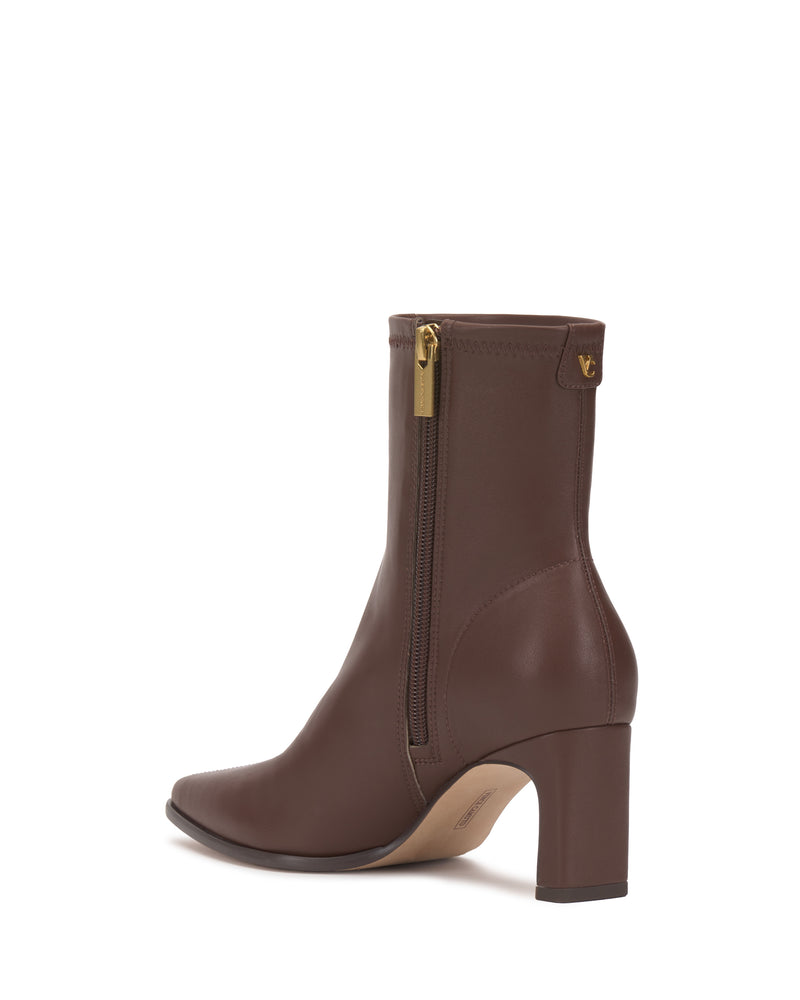 The Julea Bootie by Vince Camuto is a brown leather ankle boot featuring a mid-height block heel, pointed toe, and a side zipper with a gold pull tab.