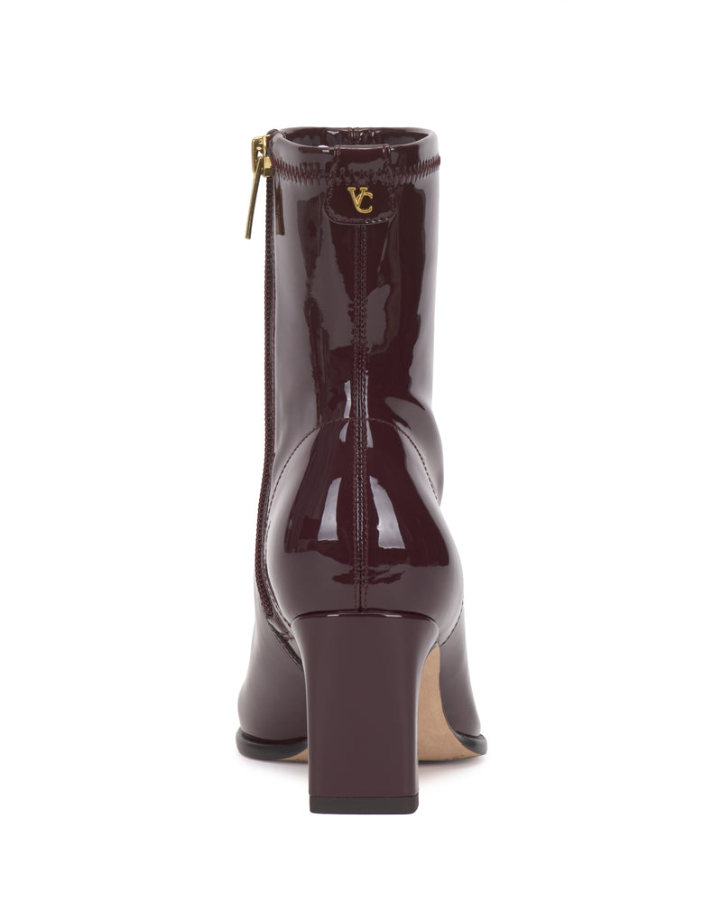 Back view of a dark burgundy patent leather Vince Camuto Julea Bootie with a block heel and a gold side zipper.