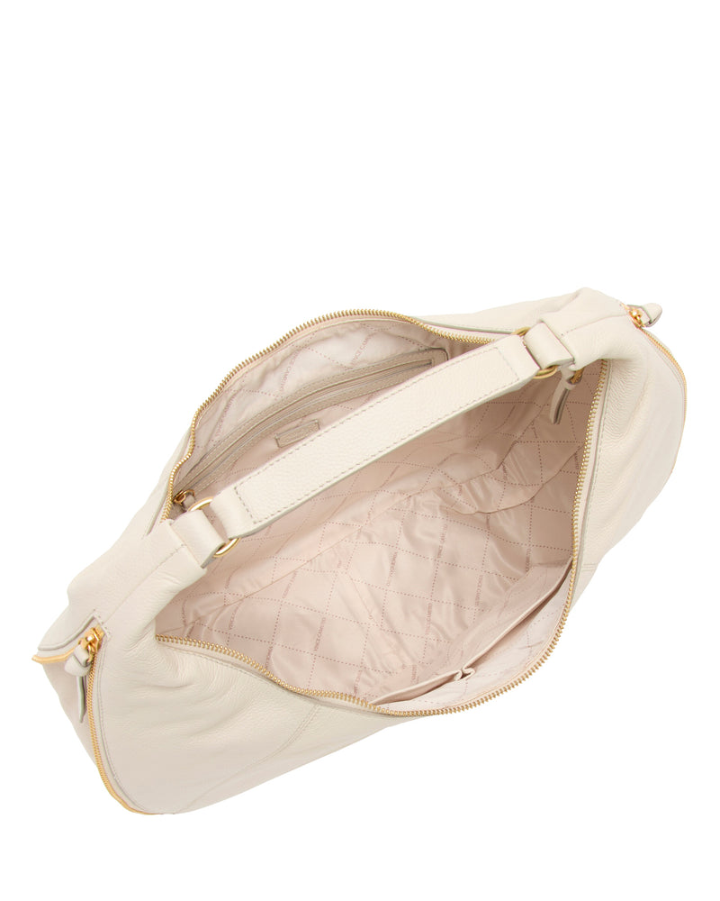 The Vince Camuto Kaela Hobo Bag features cream-colored tan leather, gold zippers, a quilted light beige interior with multiple compartments and pockets—a stylish shoulder bag seen open from above.