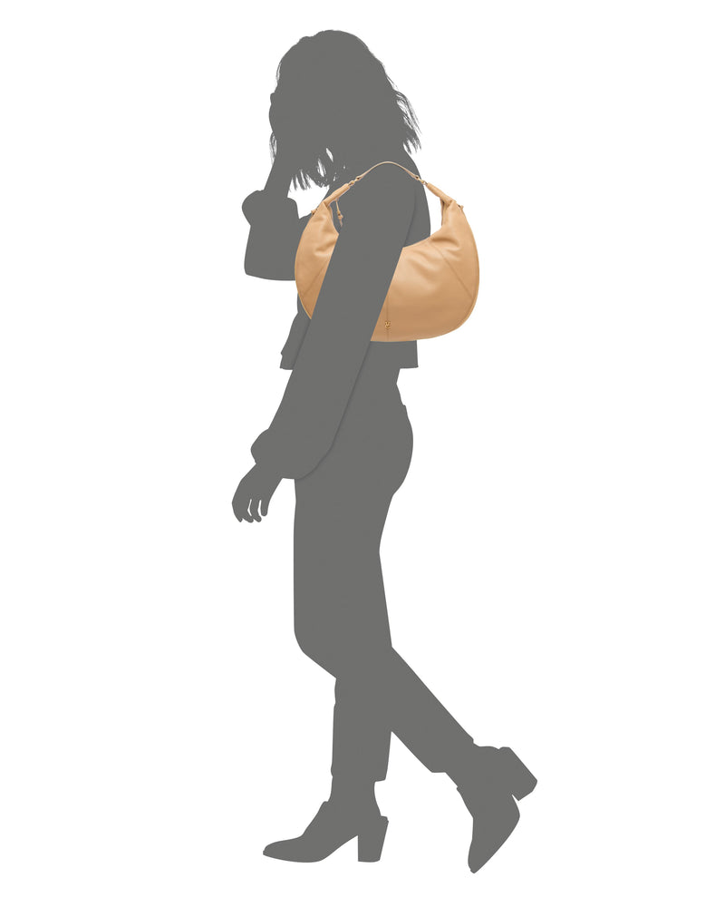 A silhouette of a person walking in heeled boots, carrying the Vince Camuto Kaela Hobo Bag on their shoulder, with their head slightly turned to the side.