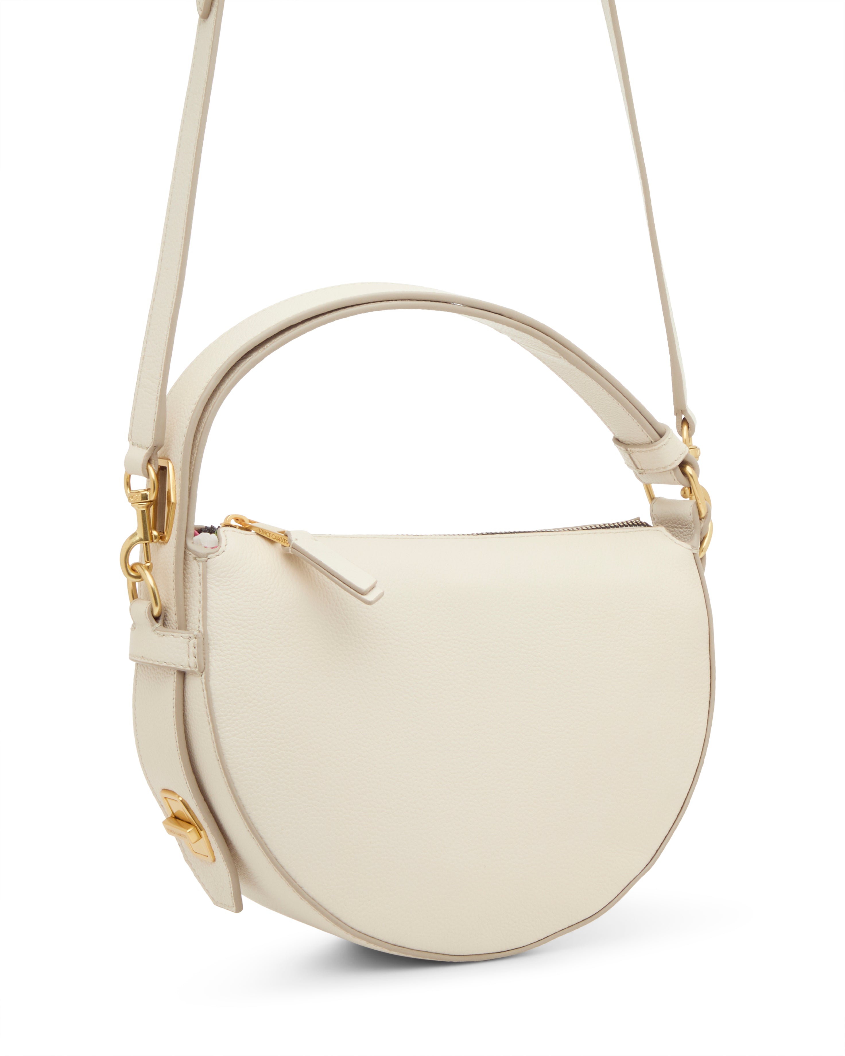 The Karla Crossbody Bag by Vince Camuto features a chic cream color, half-moon silhouette, gold hardware, top handle, long adjustable strap, and a zipper closure for a minimalist yet elegant look.