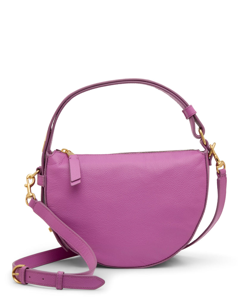 The Karla Crossbody Bag by Vince Camuto features a pink leather half-moon shape, gold hardware, a short handle, and a detachable, adjustable shoulder strap.