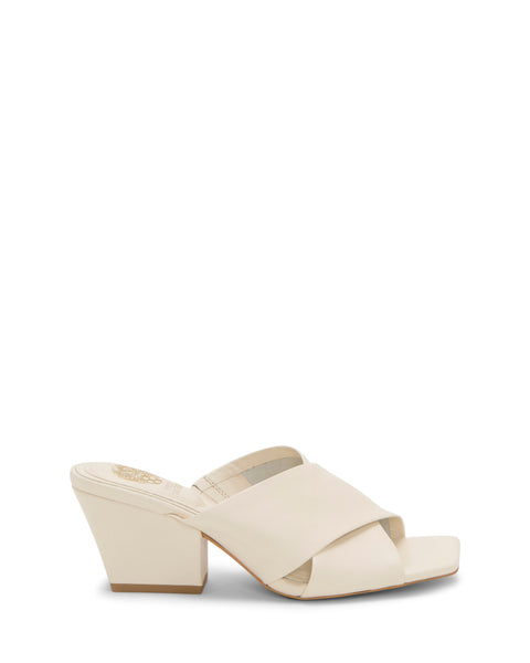 The Vince Camuto Kespa Mule is a beige leather sandal with a crisscross upper and low chunky block heel, shown on a plain white background.
