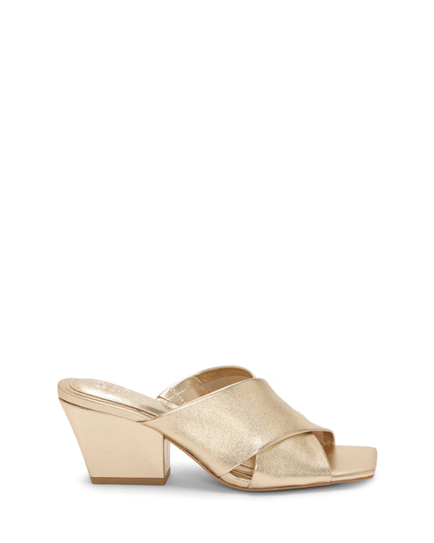 The Kespa Mule by Vince Camuto features gold leather, a chunky mid-height block heel, and a wide crisscross upper over the foot, shown on a white background.