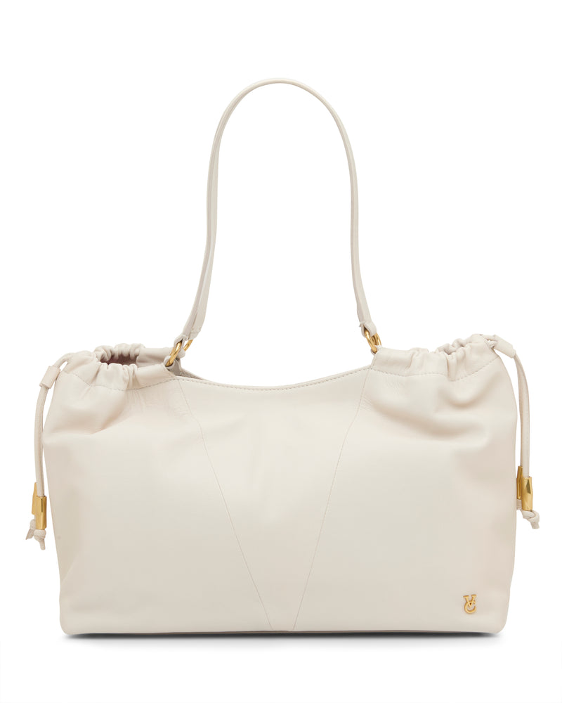 The Vince Camuto Leane Tote Bag is a cream leather handbag featuring a soft, slouchy shape, dual shoulder straps, side drawstring details, and small gold accents, including a gold logo on the bottom corner.