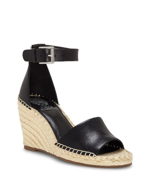 The Vince Camuto Leera Espadrille Wedge Sandal features a black leather design with a jute-wrapped wedge heel, open toe, visible stitching along the edges, and an ankle strap secured by a silver buckle.