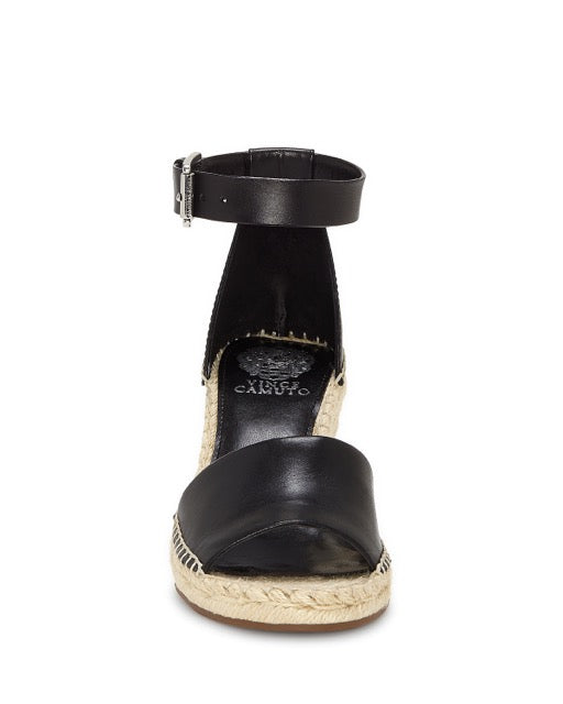 The Vince Camuto Leera Espadrille Wedge Sandal is a black sandal featuring an open toe, ankle strap with buckle closure, and a jute-wrapped platform sole. It is displayed from the front against a white background.