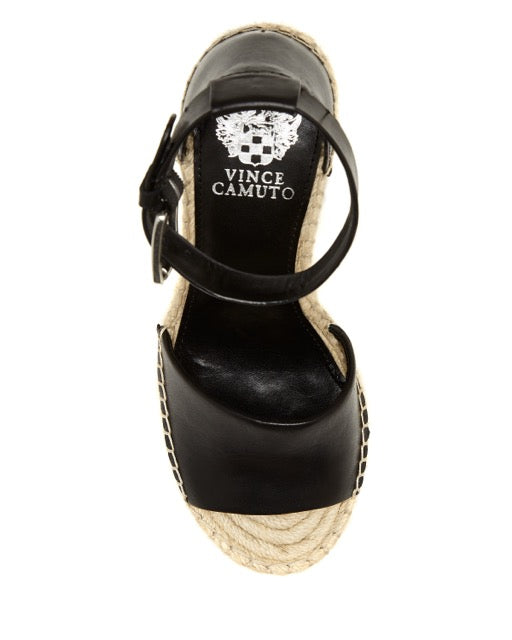 Top-down view of the Vince Camuto Leera Espadrille Wedge Sandal in black, featuring an ankle strap and a woven espadrille sole. The brand name and crest logo are printed in white on the insole.