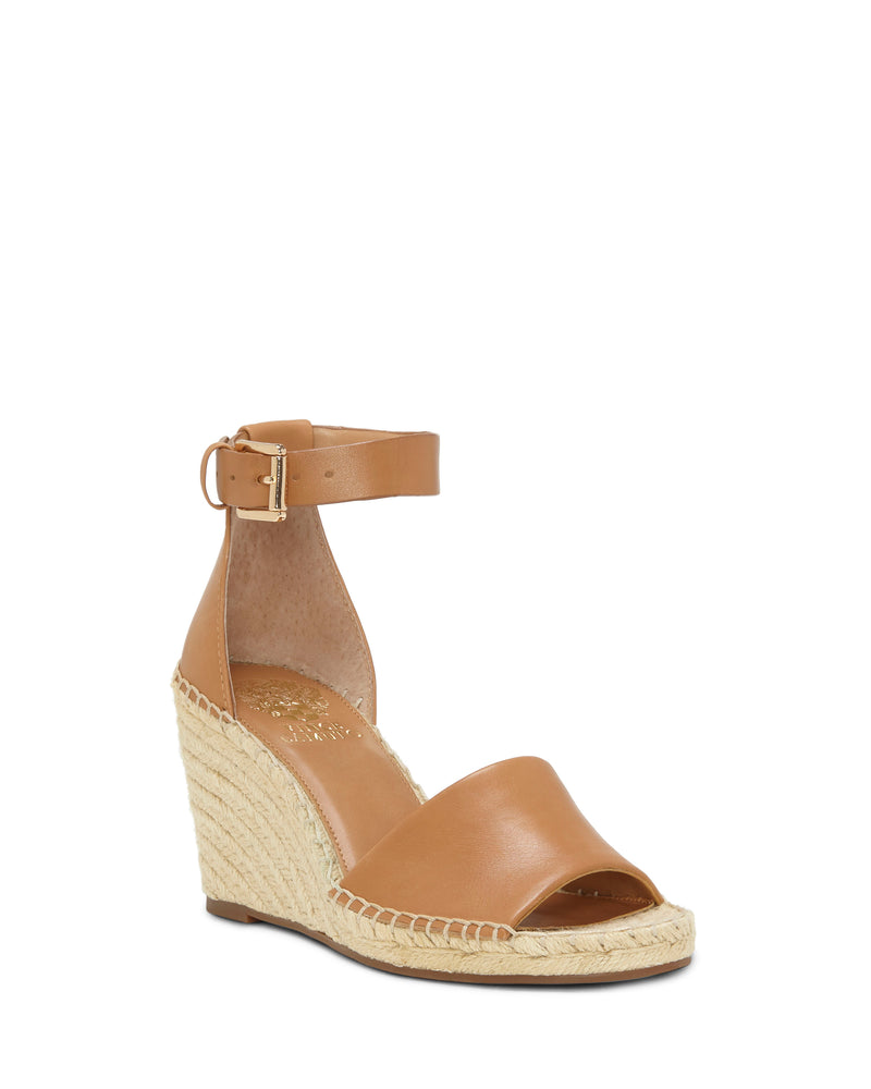 The Leera Espadrille Wedge Sandal by Vince Camuto features a tan leather upper, open toe, ankle strap with buckle, closed heel, and an espadrille-inspired woven platform sole for a stylish yet casual look.