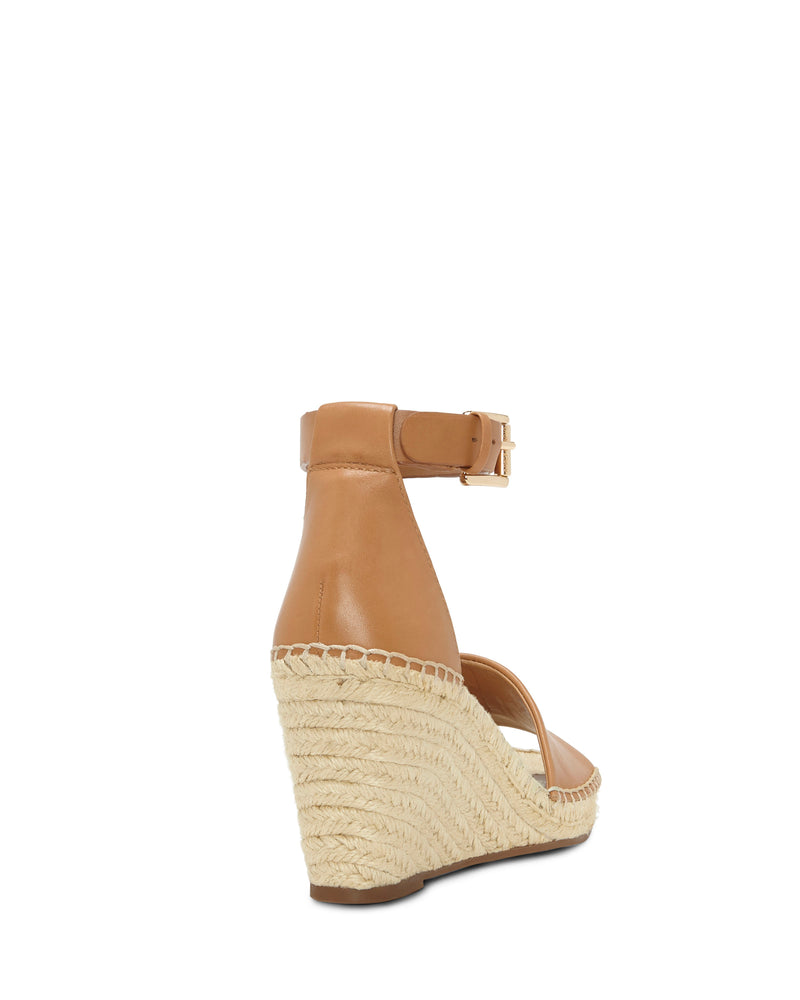 The Leera Espadrille Wedge Sandal by Vince Camuto is shown from the rear, highlighting its tan ankle strap with buckle, closed back, and high textured espadrille heel against a white background.