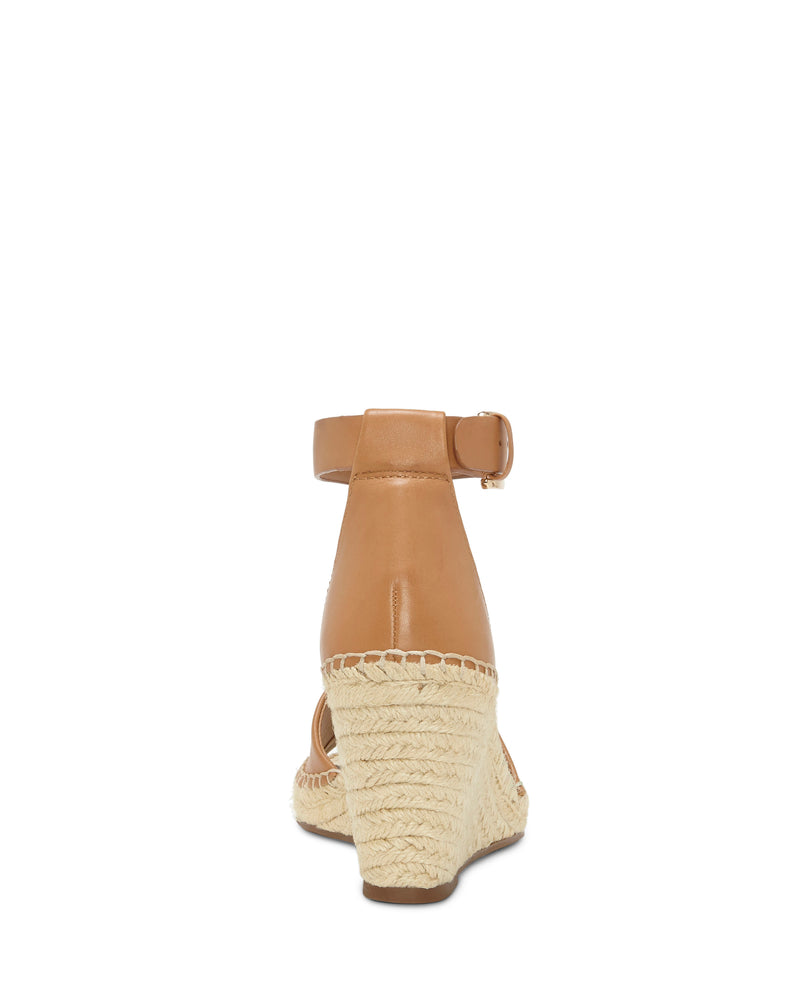 Rear view of the Vince Camuto Leera Espadrille Wedge Sandal in tan leather, featuring an ankle strap with a buckle. The platform and wedge heel are wrapped in woven, rope-like material. The sandal is photographed against a plain white background.