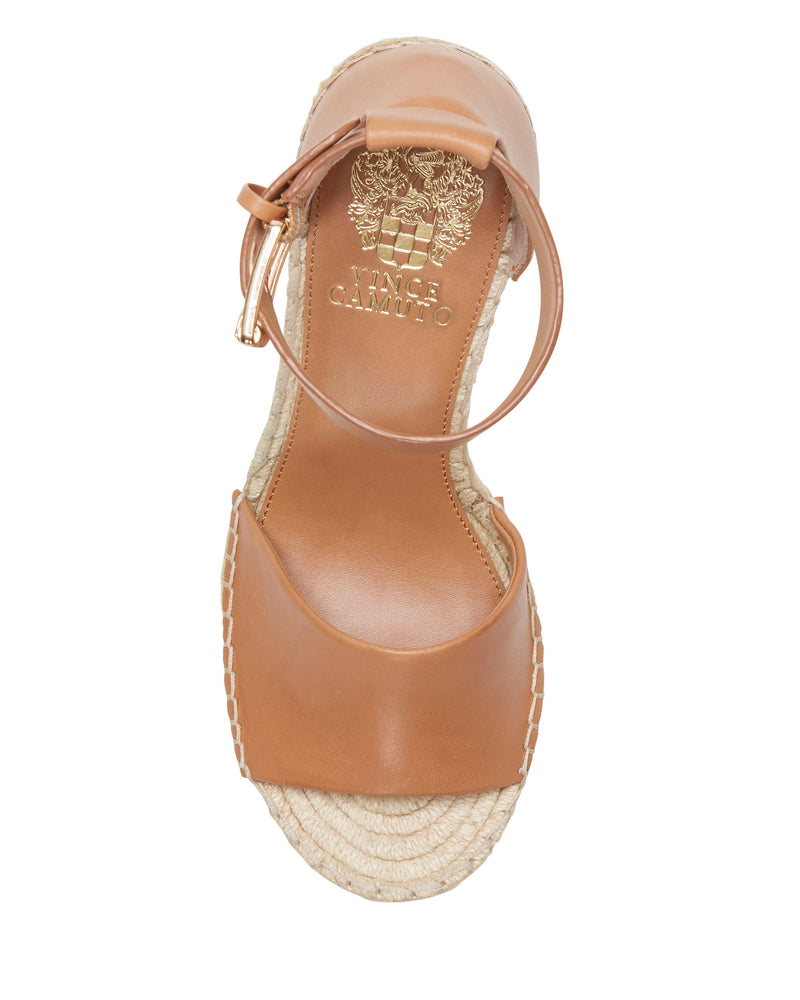Tan open-toe Leera Espadrille Wedge Sandal by Vince Camuto, featuring an ankle strap and a woven jute espadrille sole, viewed from above. The insole is detailed with a gold Vince Camuto logo and decorative emblem.