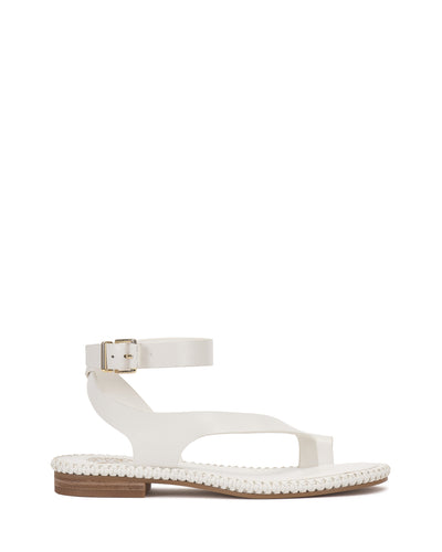 The Vince Camuto Libahs Sandal is a modern flat with a white adjustable ankle strap and buckle, open toe, cut-out design, and stitched textured sole. A low heel with a light brown accent completes the look against a plain white background.