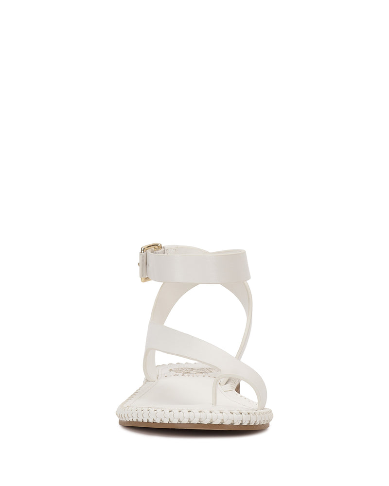 The Vince Camuto Libahs Sandal is a modern flat sandal with crisscross straps, an adjustable buckled ankle strap, and a braided edge detail on the sole.