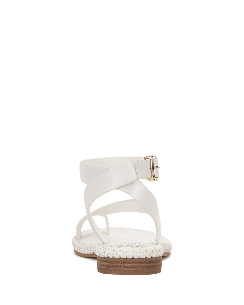 The Vince Camuto Libahs Sandal is a modern flat with crisscross adjustable ankle straps, a side gold buckle, and braided detailing on the sole, shown from the back against a white background.