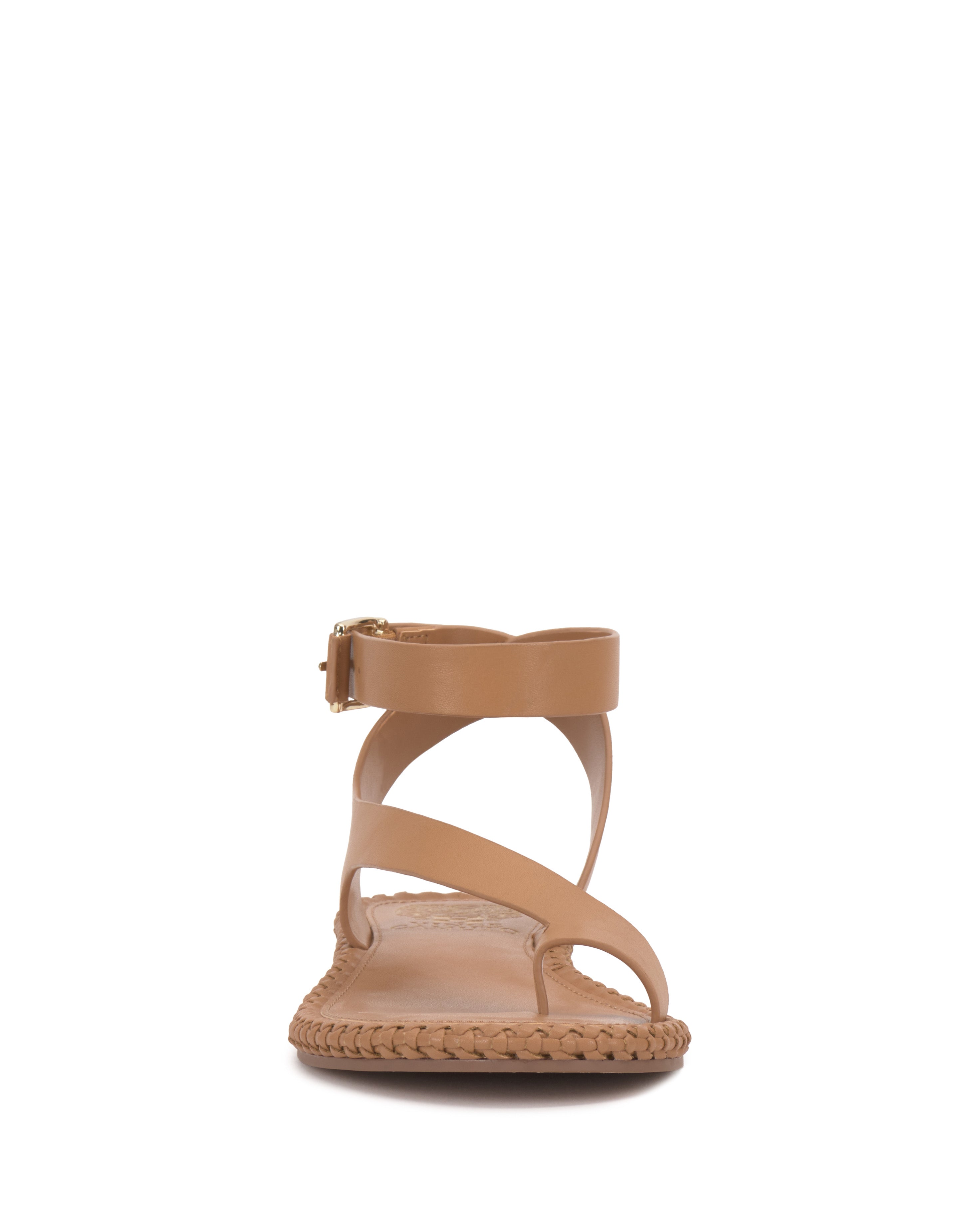 The Vince Camuto Libahs Sandal features a tan flat design with braided detailing along the sole, two crisscross toe straps, and an adjustable ankle strap with a gold buckle, shown from the front on a white background.