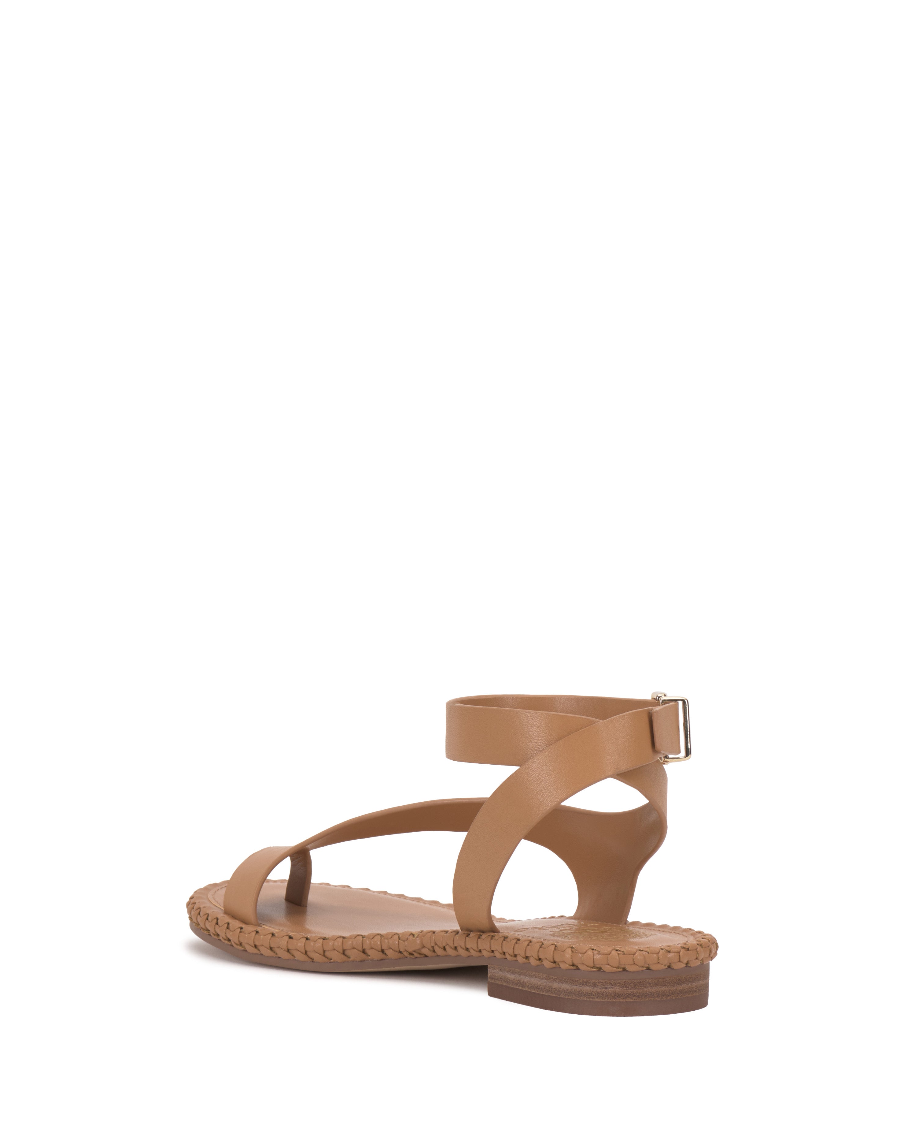 The Vince Camuto Libahs Sandal is a tan modern flat with a woven sole, open toe, and crisscross adjustable ankle strap with a small buckle, shown from the rear against a white background.