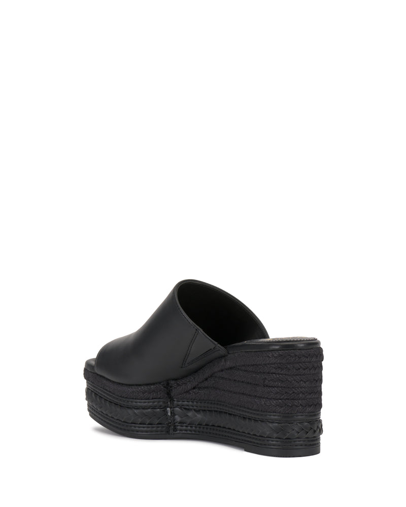 The Vince Camuto Lierna Espadrille Wedge Sandal is a black platform mule with a closed toe and textured sole, shown from the rear on a white background.