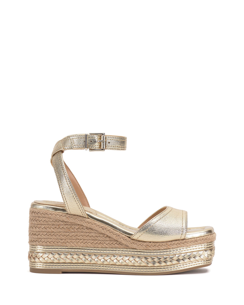The Vince Camuto Lilla Espadrille Wedge Sandal features gold metallic leather, an ankle strap with buckle, open toe, and woven jute around the thick sole for a stylish, elevated look.