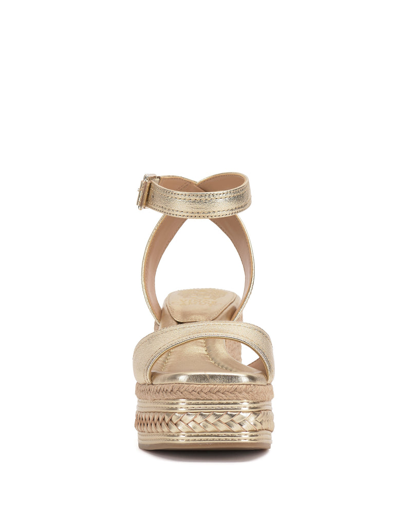 The Vince Camuto Lilla Espadrille Wedge Sandal features gold leather, an ankle strap with buckle, a front strap, and a textured woven design around the platform sole, shown here viewed from the back.