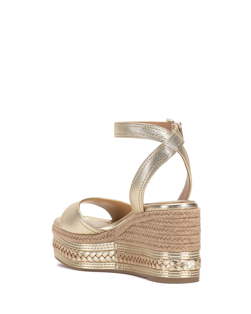 The Vince Camuto Lilla Espadrille Wedge Sandal features gold metallic leather, an ankle strap, open toe, braided jute platform heel, and a handy back zipper for easy wear.