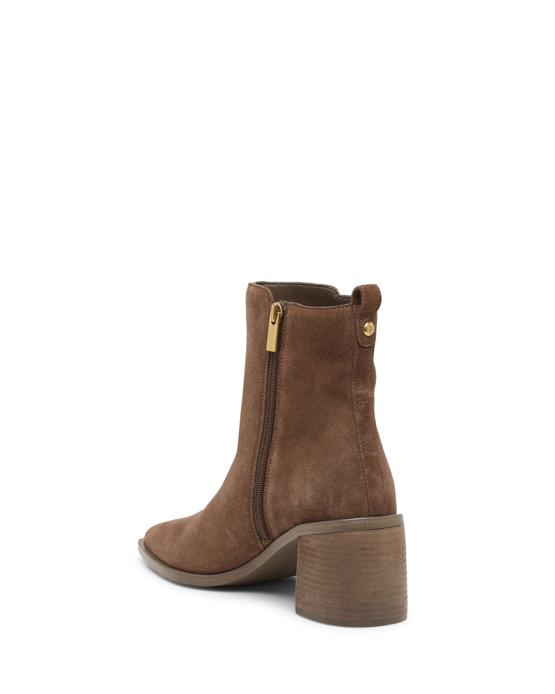 The Lorelai Bootie by Vince Camuto features rich brown suede and a sleek side zipper, combining modern style with a round toe and chunky mid-height block heel. A small gold button accents the back, while the boot is pictured on a white background to highlight its outer side and rear view.