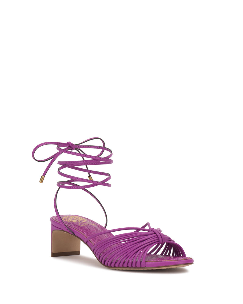 The Lory Kitten Heel Sandal by Vince Camuto is a purple ankle-tie sandal with a low block kitten heel, open toe, and long laces that wrap around the ankle and tie in a bow.