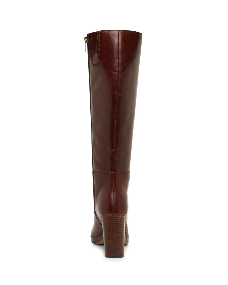 The Vince Camuto Lucina Knee High Boot is a tall, brown leather dress boot with a block heel, pictured from the back. This knee-high style features a zipper on the right side and a slightly rounded toe.